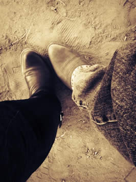 a photograph taken while looking down the subject's leg at their cowboy boots