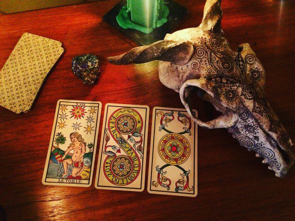 a different set of three cards placed next to the same stone, candle, and skull