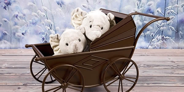 a pair of plush elephant dolls in a baby stroller