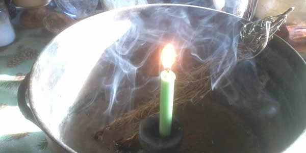 a candle burning in a cauldron along with some insence