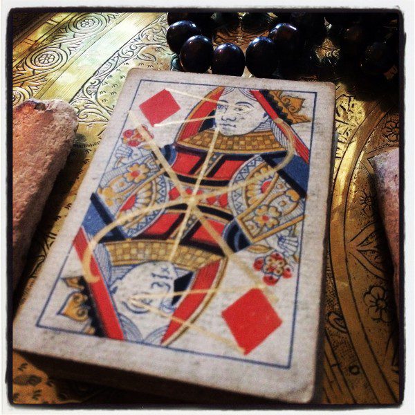 the queen of diamonds with a sigil drawn in gold on top of it