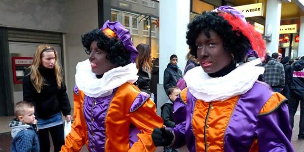 two women in black face wearing purple and orange costumes