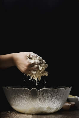 a photograph of a hand kneeding bread over a bowl