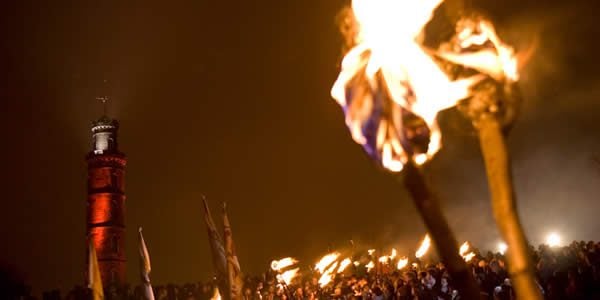 a crowd gathers at beltane with torches