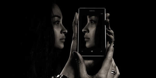 a woman holding her cell phone reflecting her profile