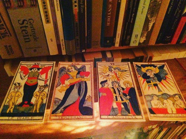 a photo of four tarot cards before books in the auhtor's library