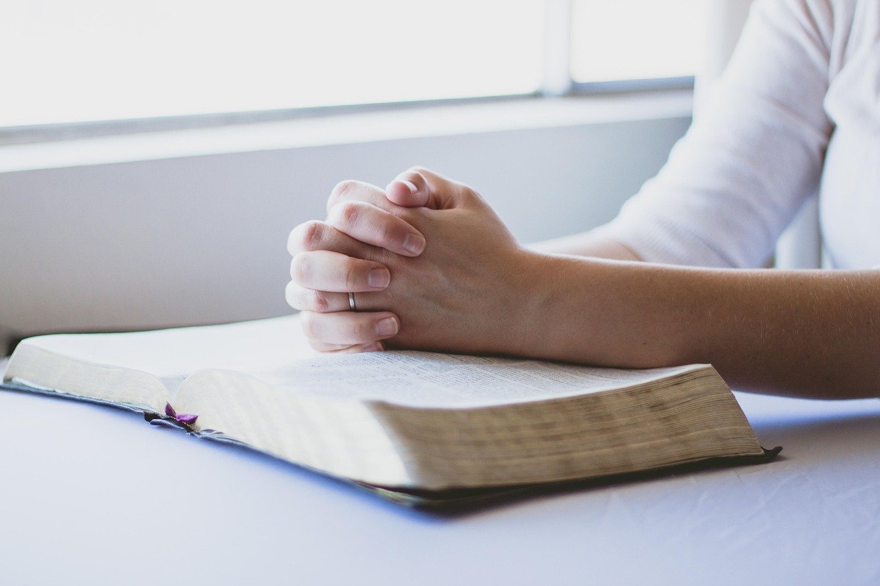 folded hands and bible