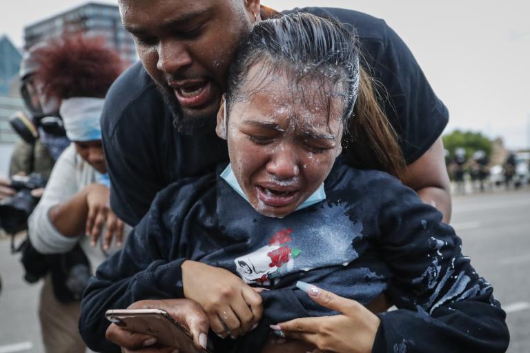 A protester reacts after being hit by pepper spray from police in Minneapolis