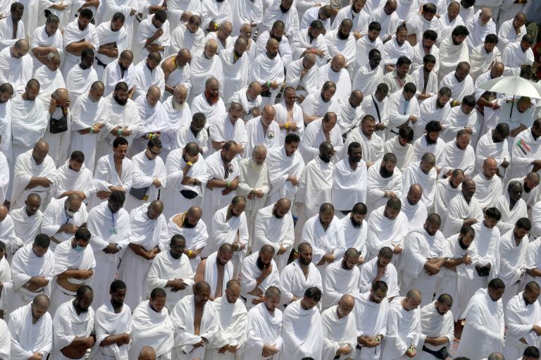 Giant crowd of Muslims all in white bowing in prayer