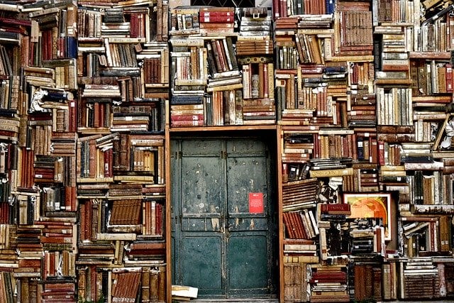 A copious amount of books surrounding a set of green doors.