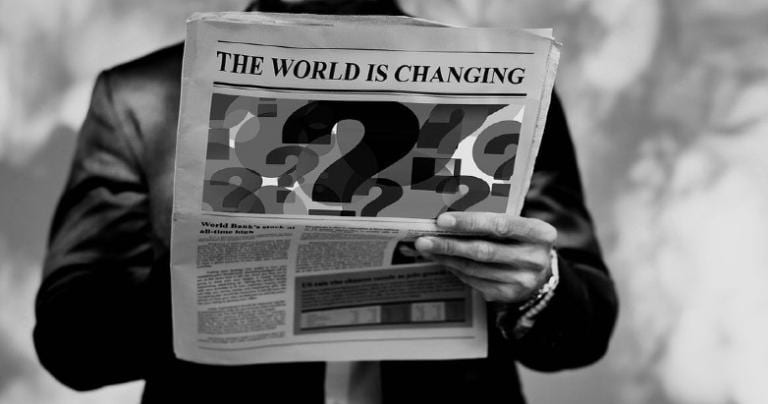 A person holding a newspaper with a headline that reads "The World Is Changing."