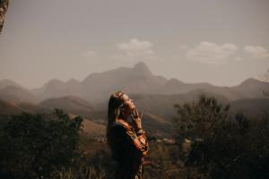 woman with hands together looking up at sky