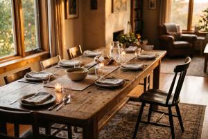 A rustic dining table set for a family meal with one chair pulled out invitingly, warm evening light
