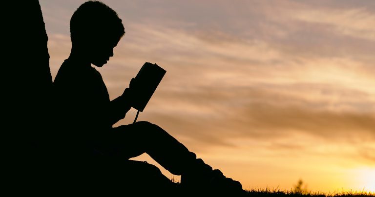 Child on hill reading book