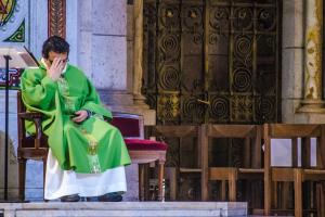 Priest in chair with head in hand.