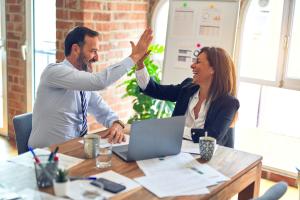 Man and woman high-fiving in office setting