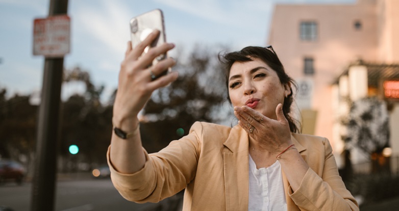 Woman blowing kisses at her cell phone