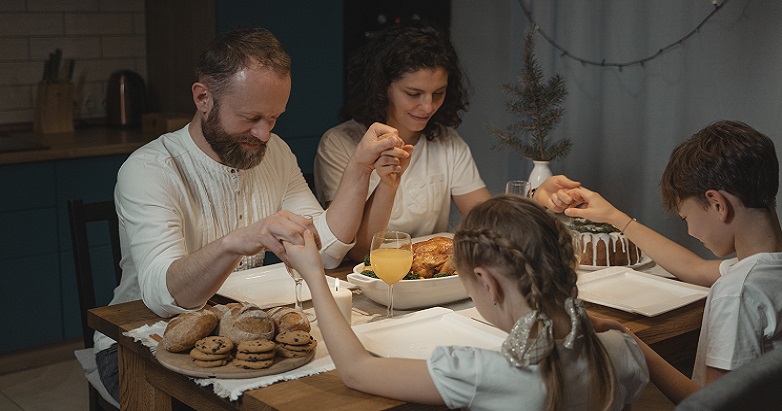 A family holding hands, praying at the sacred space in their home