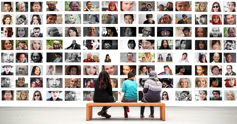 Three people sitting on bench looking at pictures of diverse faces