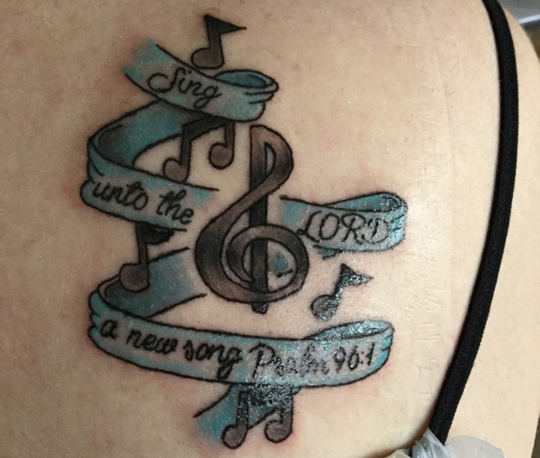 Treble clef tattoo: "Sing unto the Lord a new song. Psalm 96:1"
