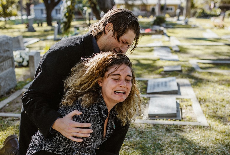 When Prayers of Protection and Healing Fail. Man and woman crying in cemetery.