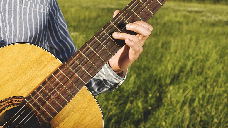 Calling Jason Aldean a Heathen—"Try That in a Small Town!" Man's hands playing guitar