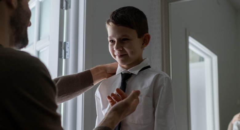 Father helping son put on a tie