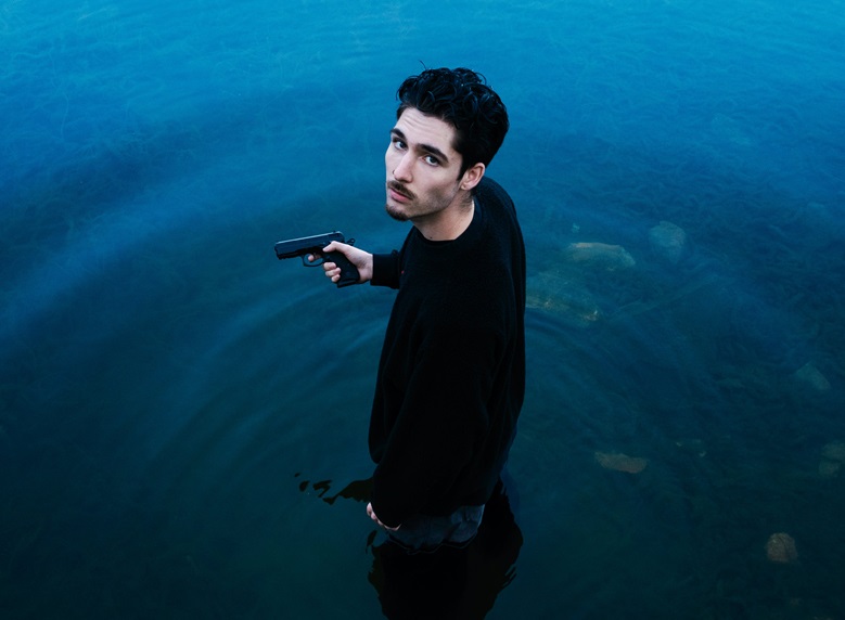 Young man with a gun standing in the lake
