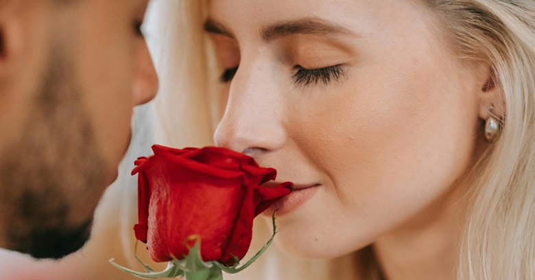 Woman smelling rose given to her by a man