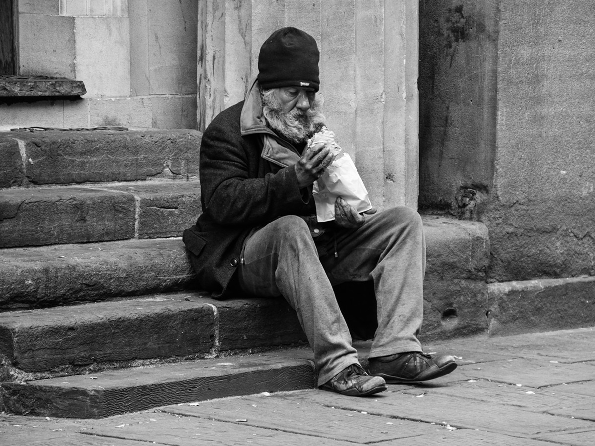 Homeless man on steps with a bottle inside a paper bag