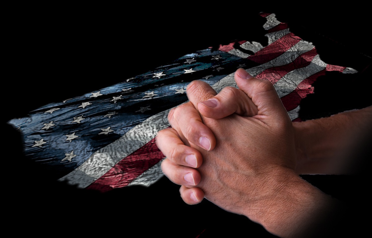 Praying hands atop an America-shaped US flag