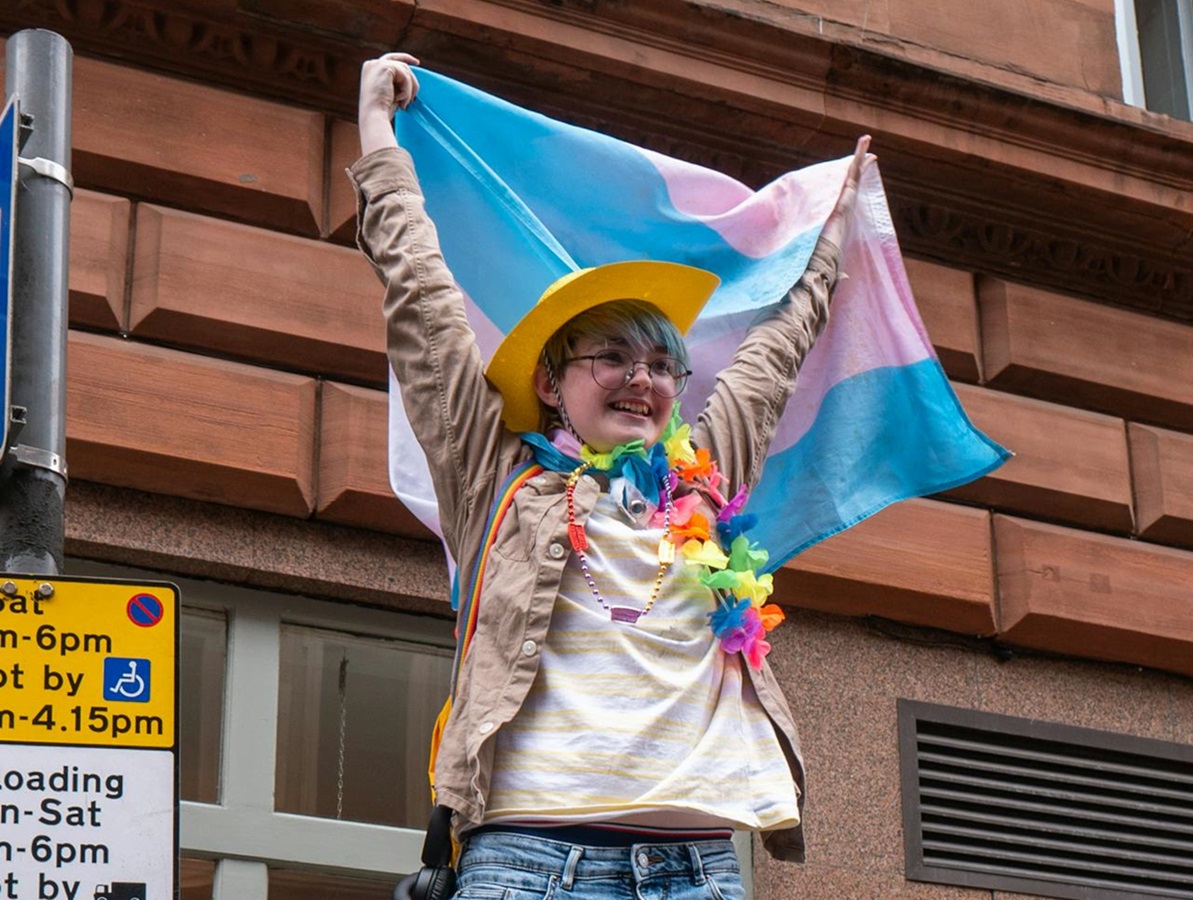 Trans person holding up trans flag