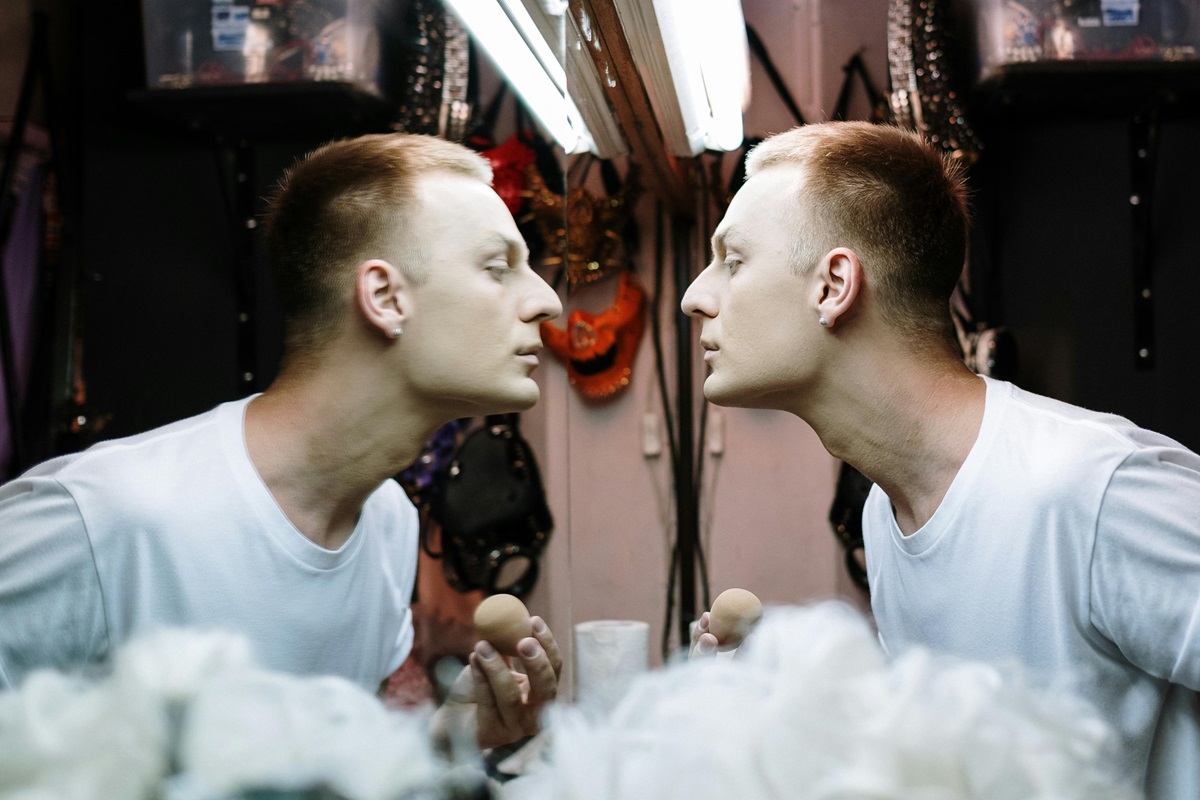 Man looking in the mirror, putting on makeup