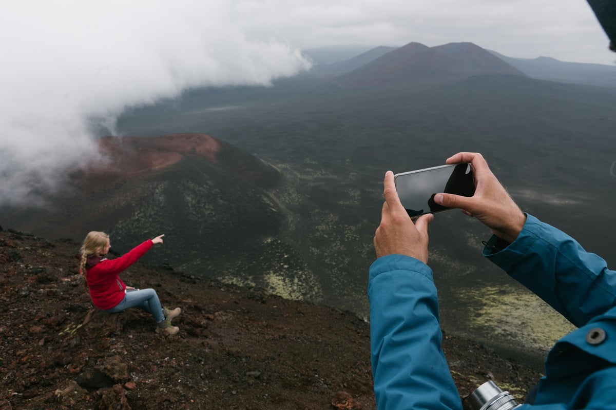 Daughter is pointing to the amazing vista but father is taking a picture of his daughter, the real inspiration.