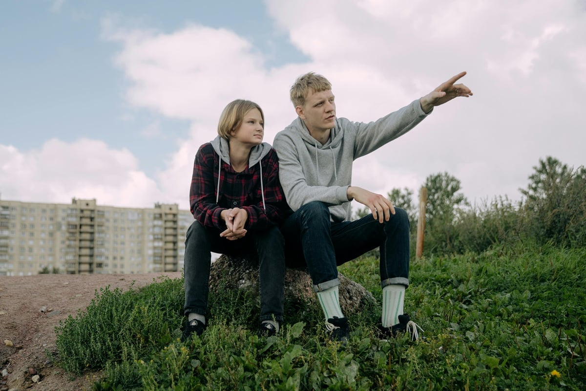 Two brothers sitting together, with one pointing into the distance