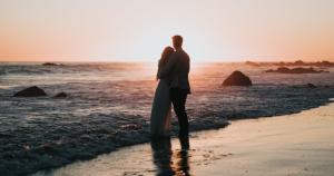 couple hugs on beach at sunset
