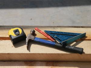 a hammer, measuring tape, pencil, and speed square