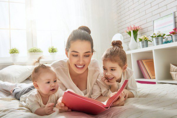 happy loving family. pretty young mother reading a book to her daughters