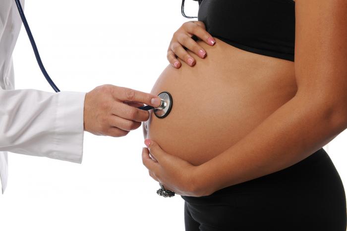 Pregnant woman being examine by a doctor with a stethoscope isolated on white
