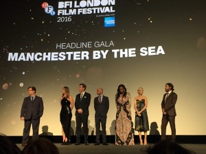 The cast of Manchester by the Sea dressed up for the release of the movie, standing under a title of the movie. 