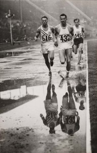 Three men running in a track covered with water puddles in the 1948 Olympic Games in London