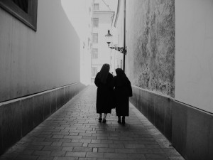 two nuns walking through an empty alleyway into light.