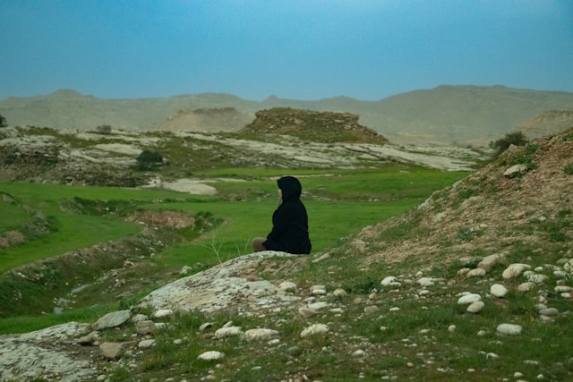 Lonely person sitting in vast landscape representing despair grumbling and testing during difficult faith seasons