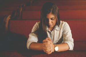 A girl praying in a church pew