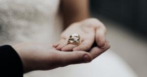 Couple holding wedding rings.