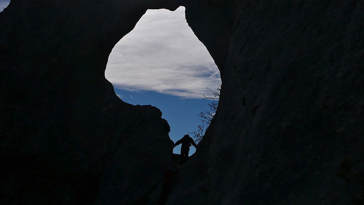 A person looks out of an opening in the rocks