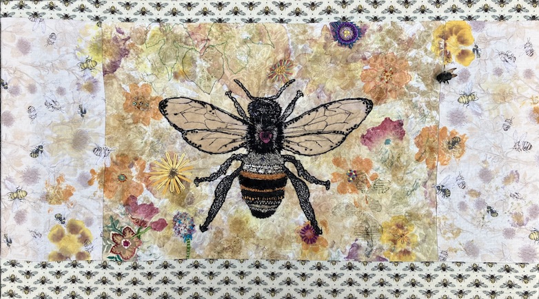 Embroidered bee on a fabric dyed with pressed flower