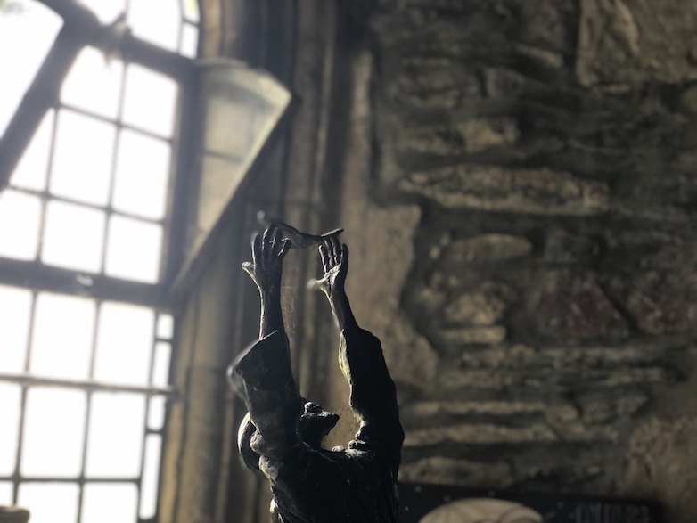 A statue of St. Columba reaching to a dove in the chapel of Iona Abbey, Scotland