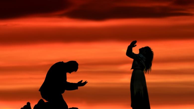 Head bowed in prayer and hands lifted in prayer with sunset background