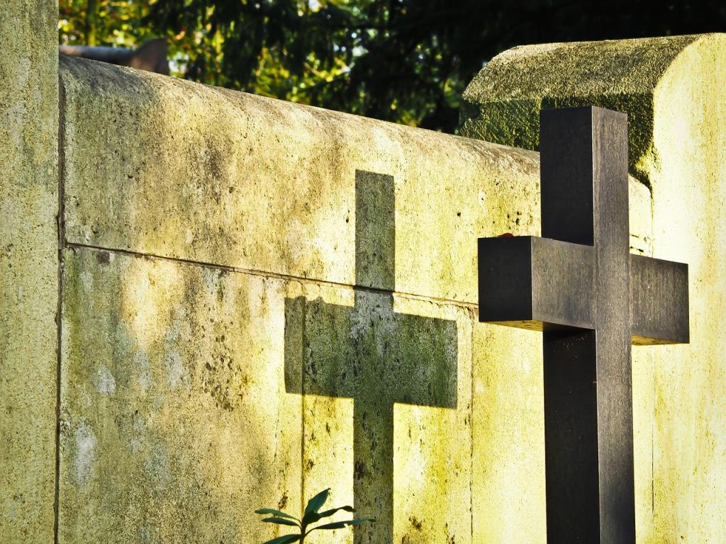 Graveyard with cross casting shadow on a wall
